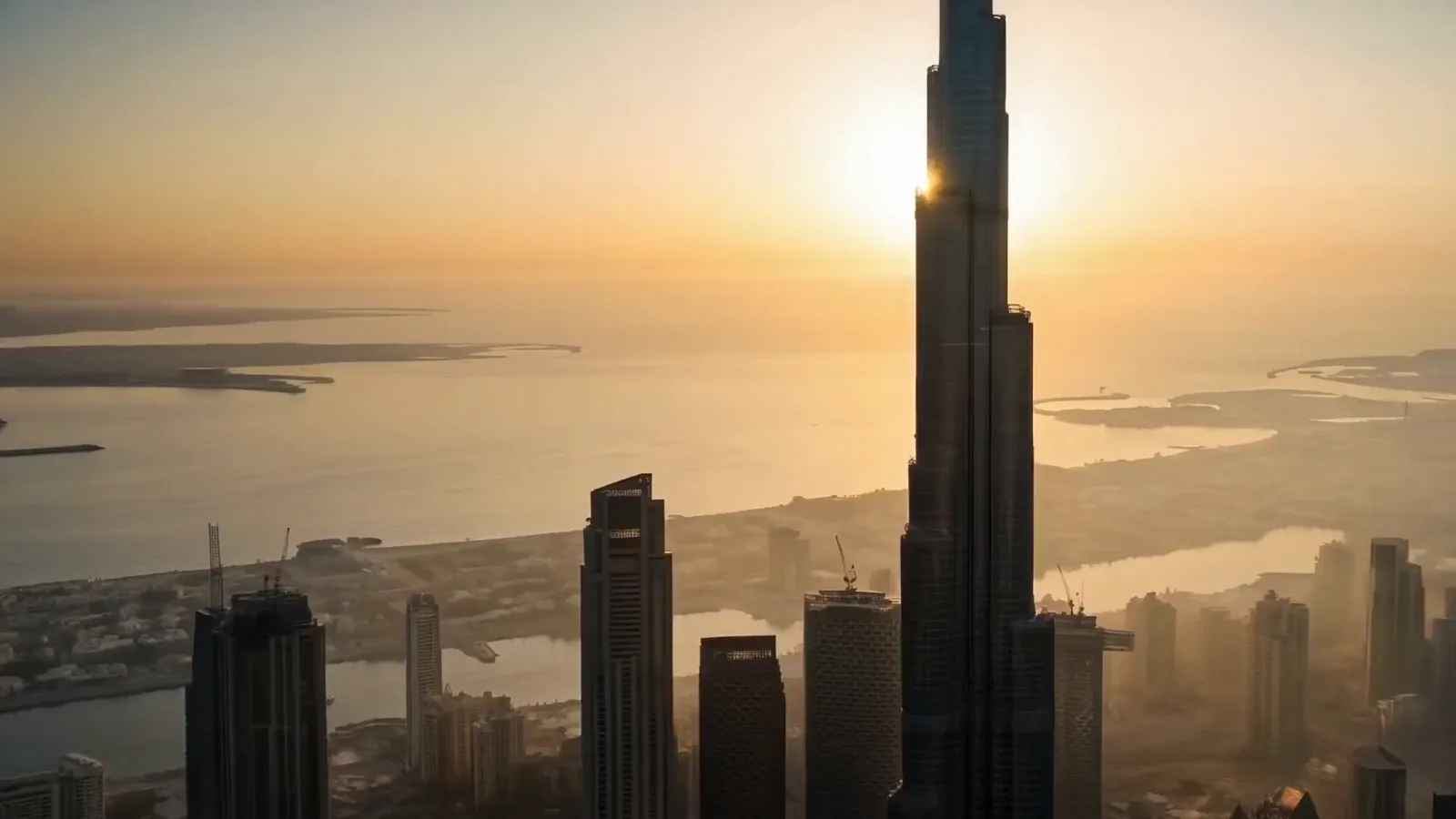 Aerial view of Dubai at sunrise, the Burj Khalifa rising against the sun over the sea